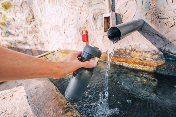 Pouring water from a spring source at camping or hiking. Clean looking water can be contaminated and dangerous to health
